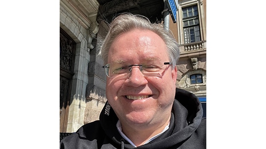 Mann lächelt vor einem Gebäude