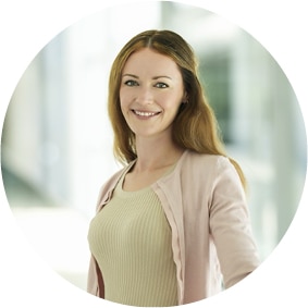 Frau steht in einem Büroflur und lächelt