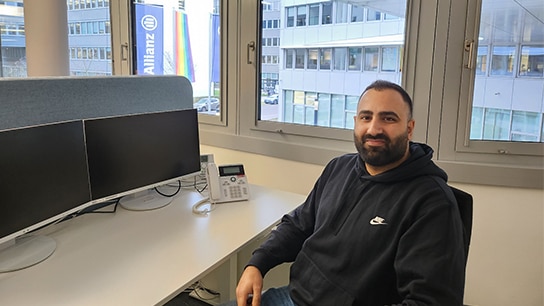Mann sitzt an seinem Arbeitsplatz mit zwei Bildschirmen
