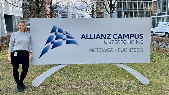 Frau steht vor dem Unterföhring Campus Schild in München