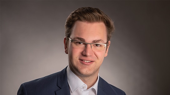 Mann in Anzug vor einem grauen Hintergrund 