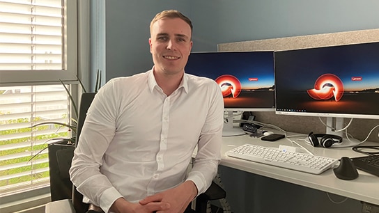 Mann in Hemd vor zwie Bildschirmen im Büro