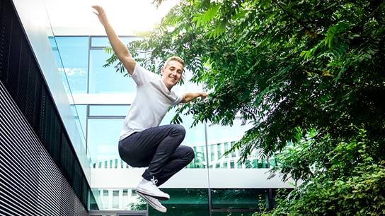 Mann springt vor einem Gebäude