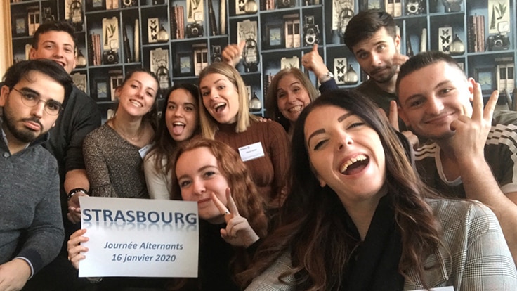 Un groupe de jeunes employés montrant joyeusement un geste de « victoire » à la caméra, souriant et célébrant ensemble.