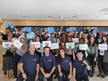 Des employés avec des expressions joyeuses, tenant des pancartes et célébrant ensemble.