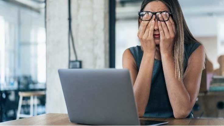 Une collègue se frotte les yeux et soulève ses lunettes alors qu'elle est assise devant un ordinateur portable