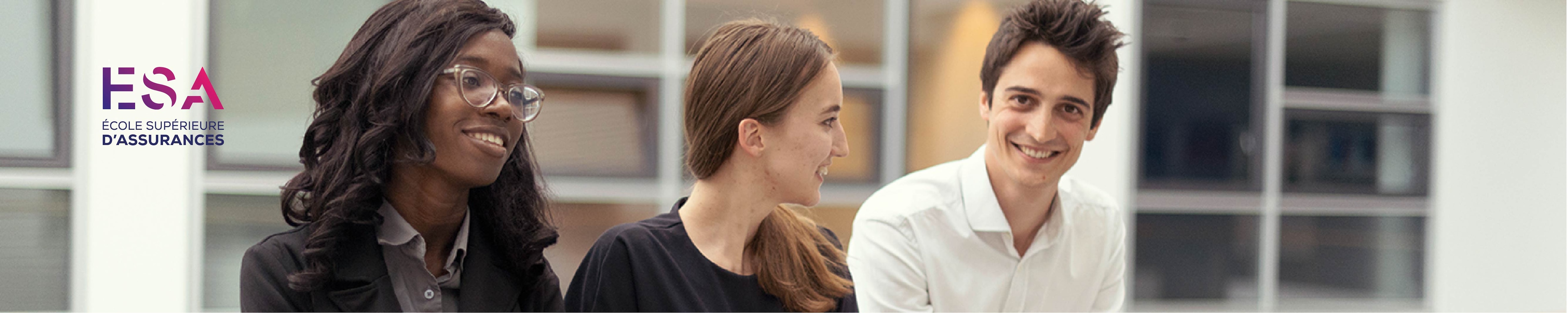 Deux jeunes femmes sont assises, souriantes, à côté d'un homme qui regarde aimablement la caméra.