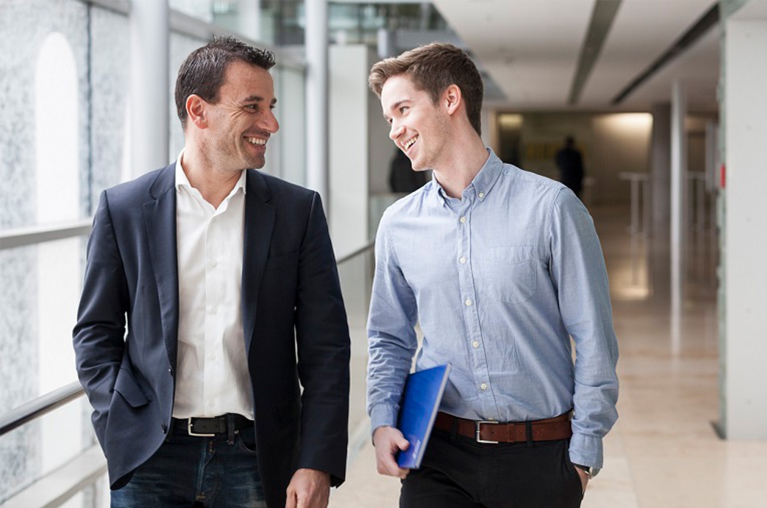 Deux collègues ayant une conversation joyeuse, souriant et interagissant l'un avec l'autre dans un environnement de bureau