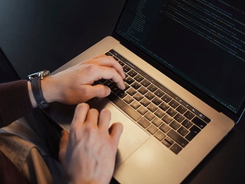 Toma de primer plano de las manos sobre el teclado de una computadora portátil.