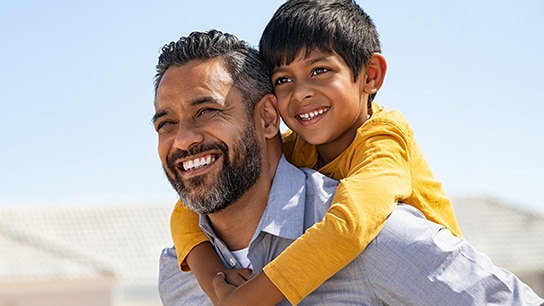 A man with a kid on his shoulder smiling