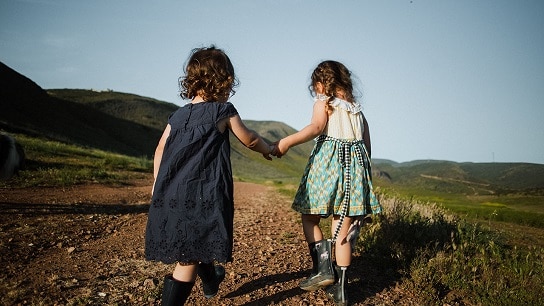 Two girl kids holding their hands and walking