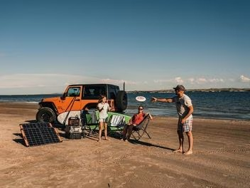 A family relaxing on the beach next to a solar-powered vehicle