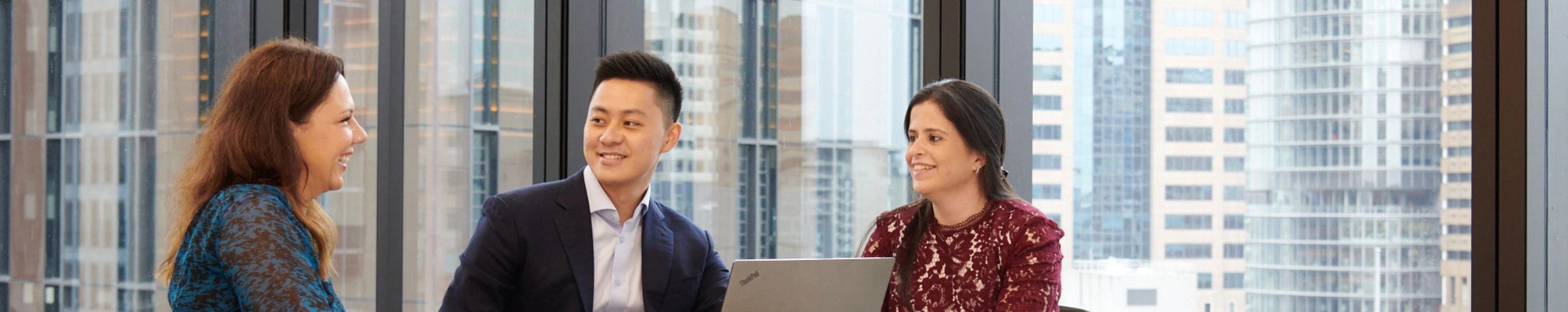 Colleagues engaged in discussion while working on a laptop.
