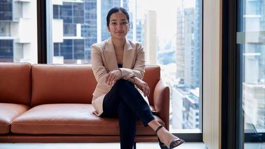 A woman with a genuine smile sits on a couch creating a warm and inviting atmosphere