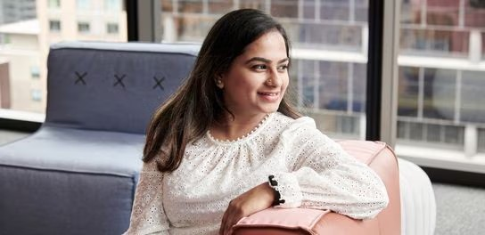 A woman on a pink couch in an office, exuding a sense of calm and creativity in a well-designed workspace
