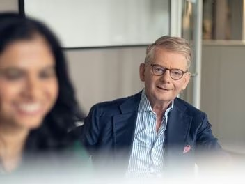 A senior employee and a younger colleague smiling and engaging in a conversation