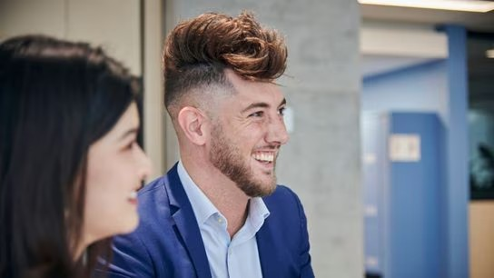 In an office environment, a man and woman share smiles, reflecting a collaborative and friendly atmosphere