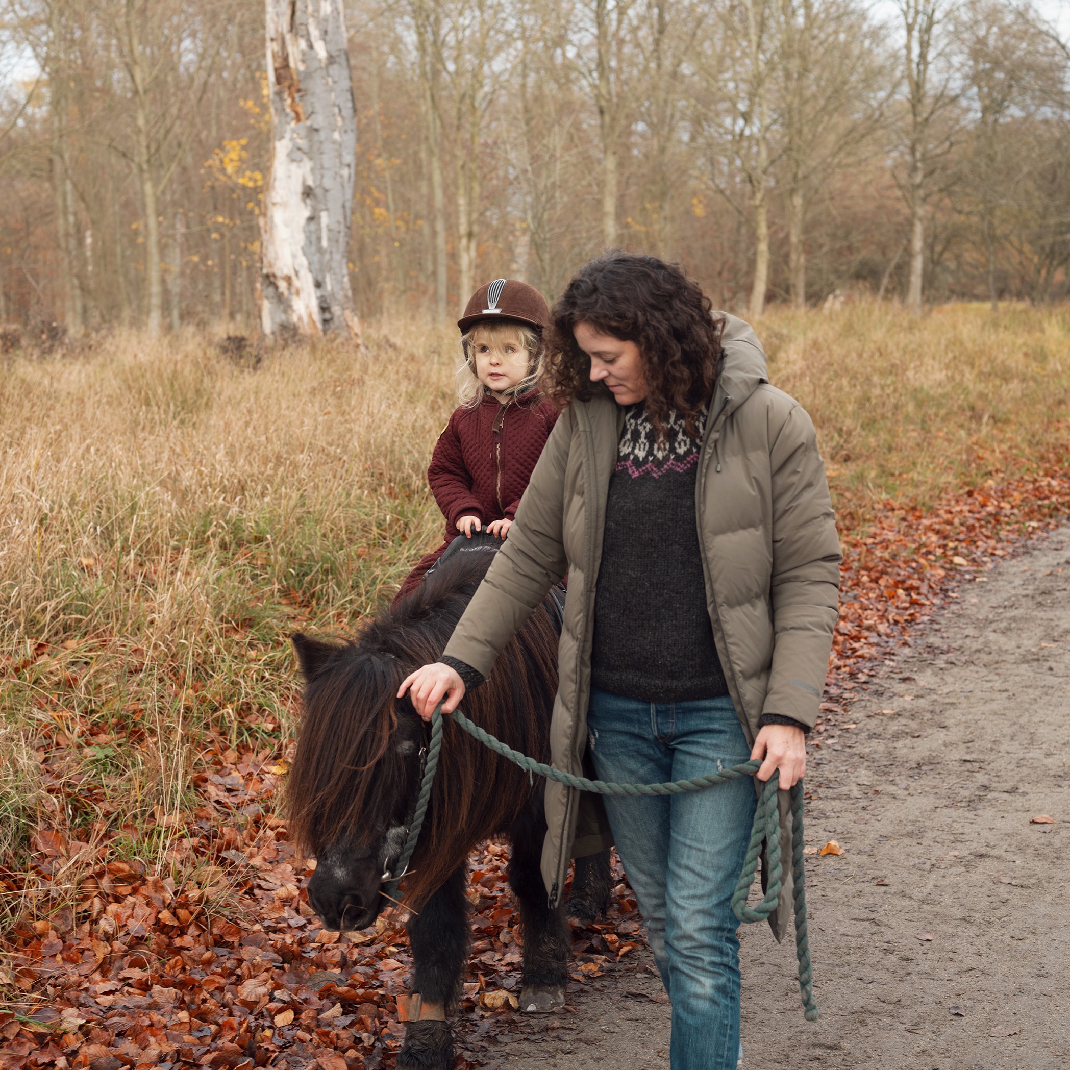 Woman leading a pony with child riding