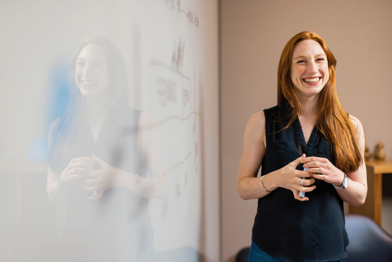 A cheerful woman in front of a white board