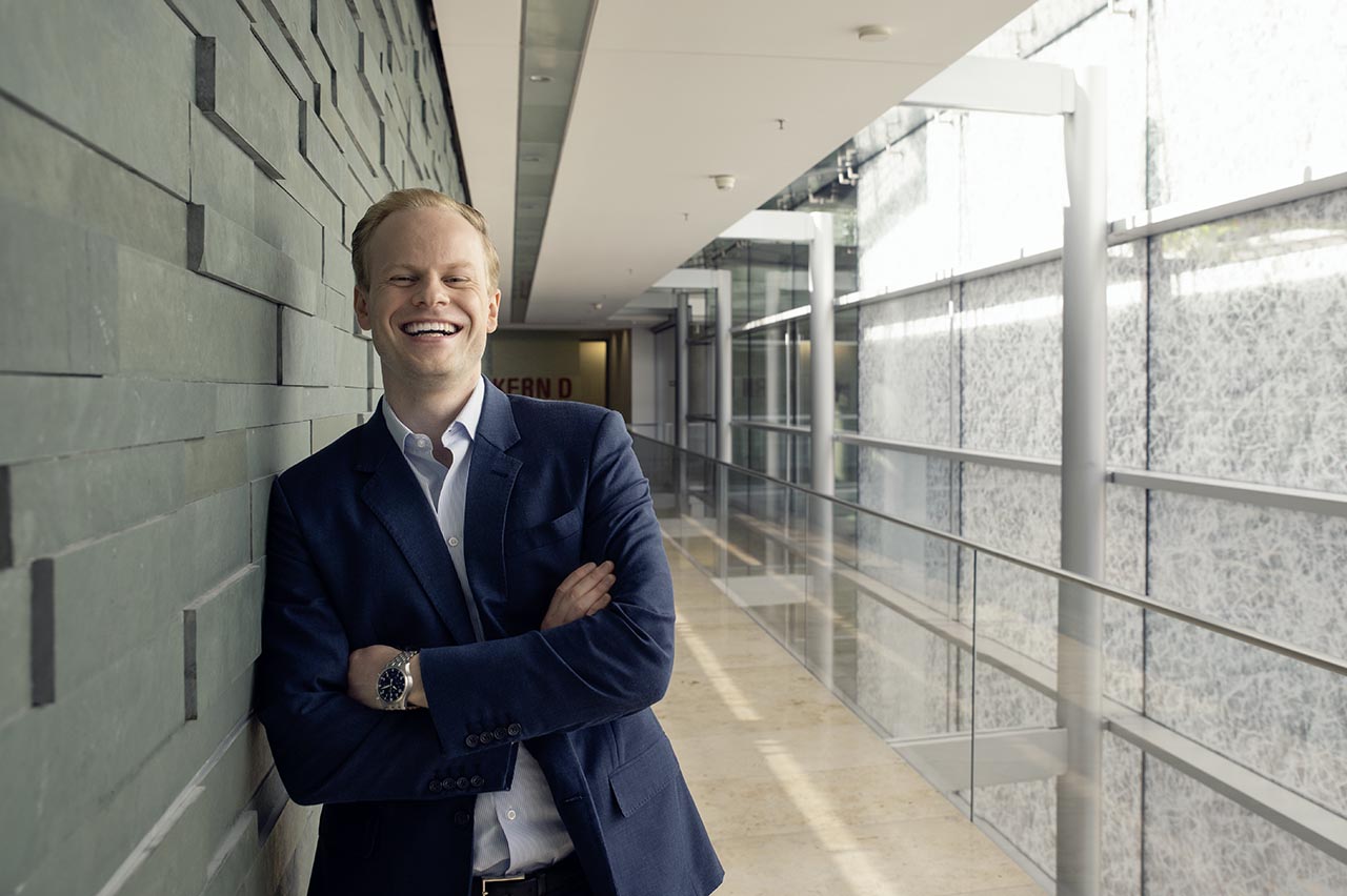 Allianz employee in office suit, smiling and looking cheerful.