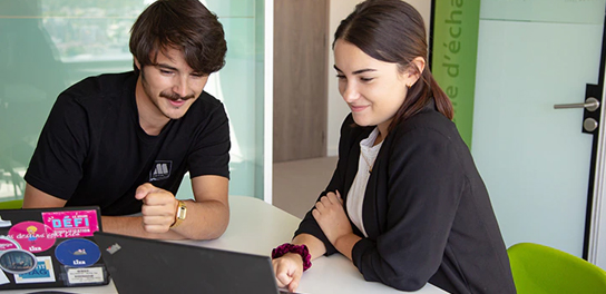 Deux collègues discutent en travaillant sur un ordinateur portable