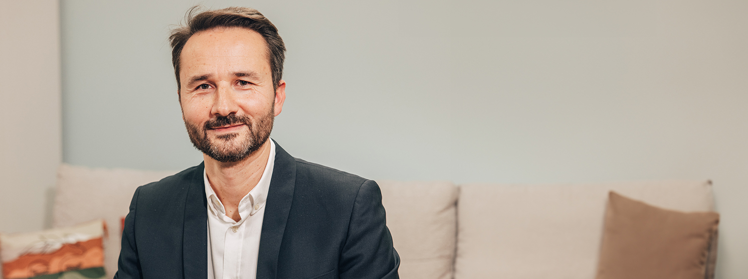 Allianz France Employee sitting on sofa smiling