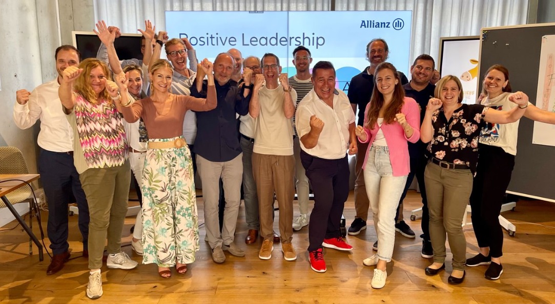 Group of leaders standing in front of screen showing text "Positive Leadership"