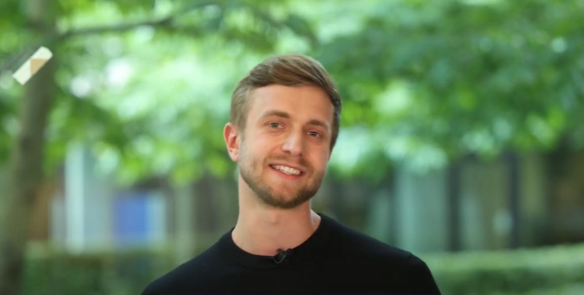 Mann steht vor einem grünen Hintergrund