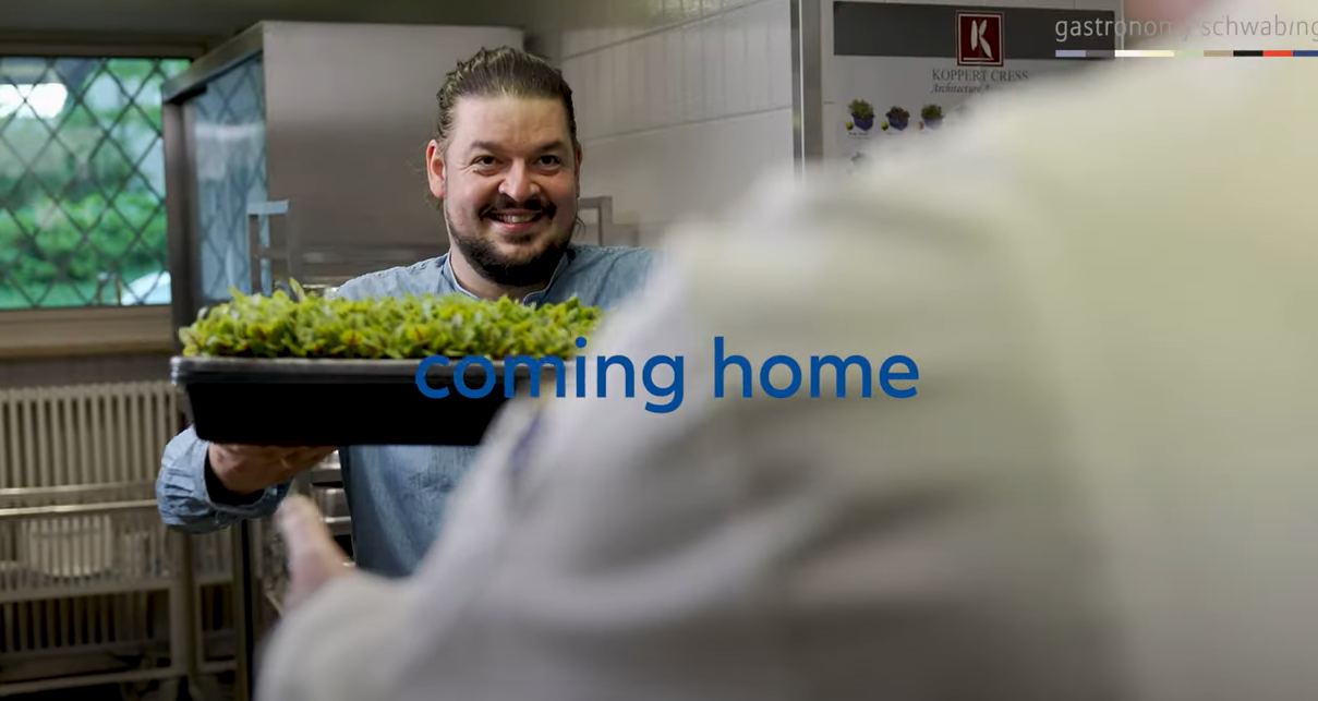 Mann steht mit Kräutern in der Hand in einer Küche