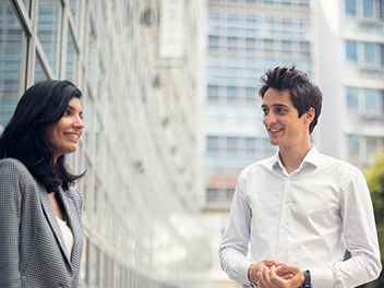 Two colleagues engaged in a happy conversation outside a modern office building
