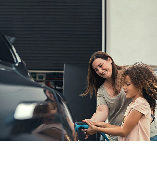 A mother and daughter at a charging station, charging their electric vehicle