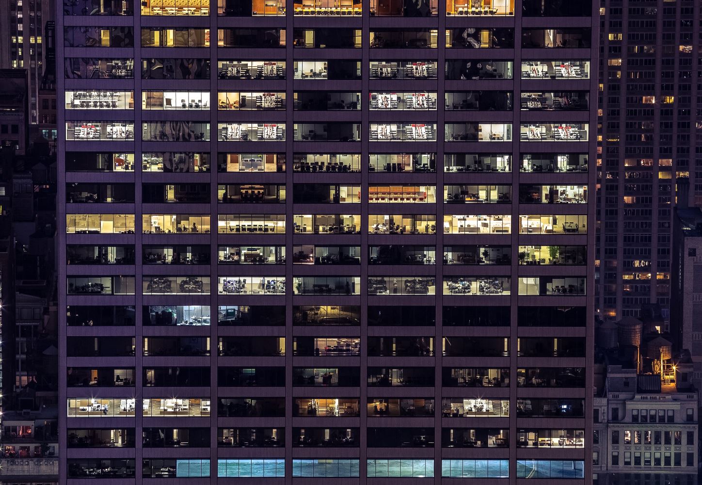 Grid of illuminated windows in a modern high-rise office building at night