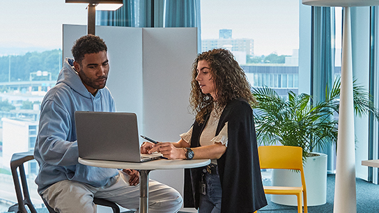 picture of students sitting on a table looking at a laptop