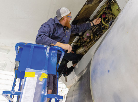 Aviation Maintenance technician on lift checking an aircraft