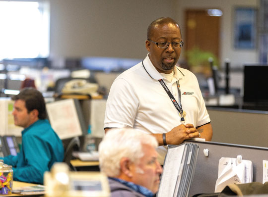 Office workers talking to each other at a cubicle