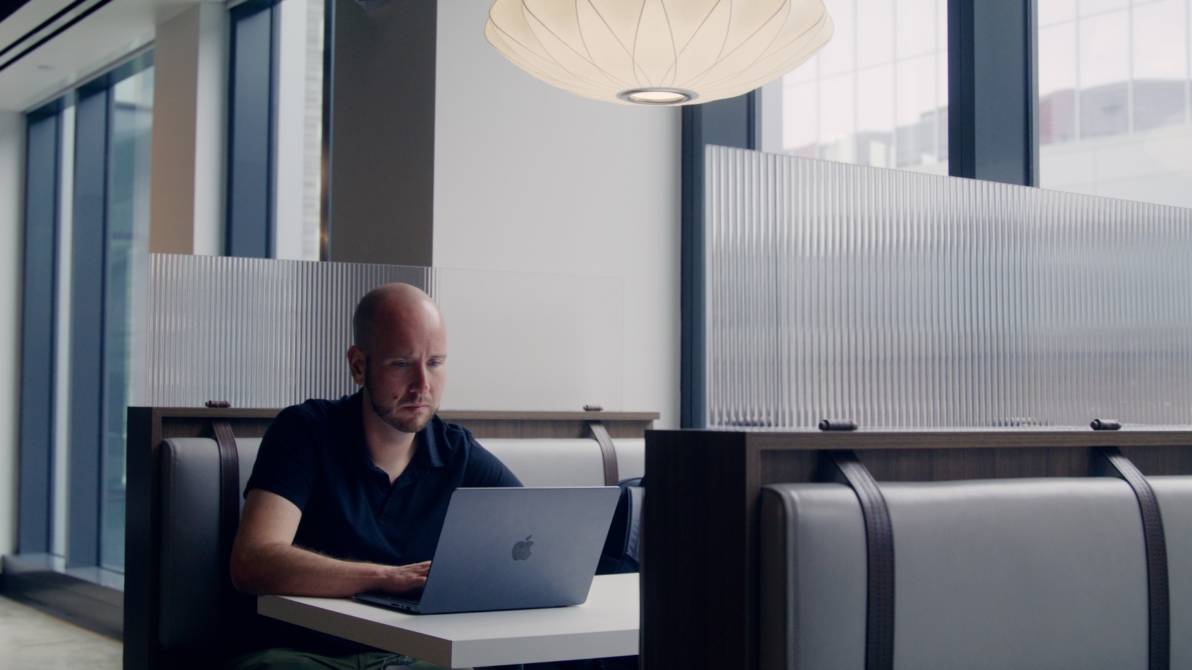 Mike Ellis, customer project manager at athenahealth sitting in a booth working on a laptop