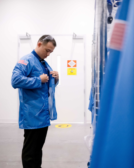 Ryan, a procurement manager, puts on a blue BAE Systems smock as part of his PPE before entering the manufacturing floor. 