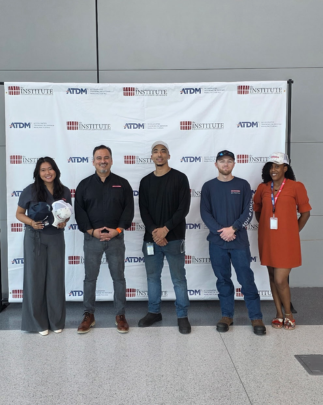 Five people pose indoors in front of an ATDM and Institute for Advanced Learning and Research backdrop at a defense manufacturing training hiring event.