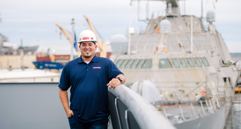 Jose, a craft supervisor, on our Jacksonville Maritime Solutions team poses for a photo with a military vessel behind him.