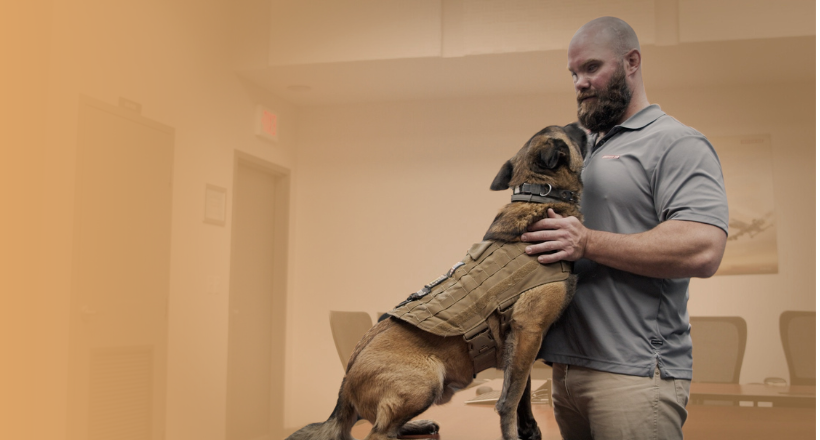 Tom, a BAE Systems team member and military veteran, pets his service dog. 