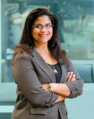 Neeta, a BAE Systems program director, smiles for a headshot in a company lobby.