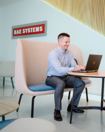 Tony, a program manager, works on his laptop in a BAE Systems lobby.