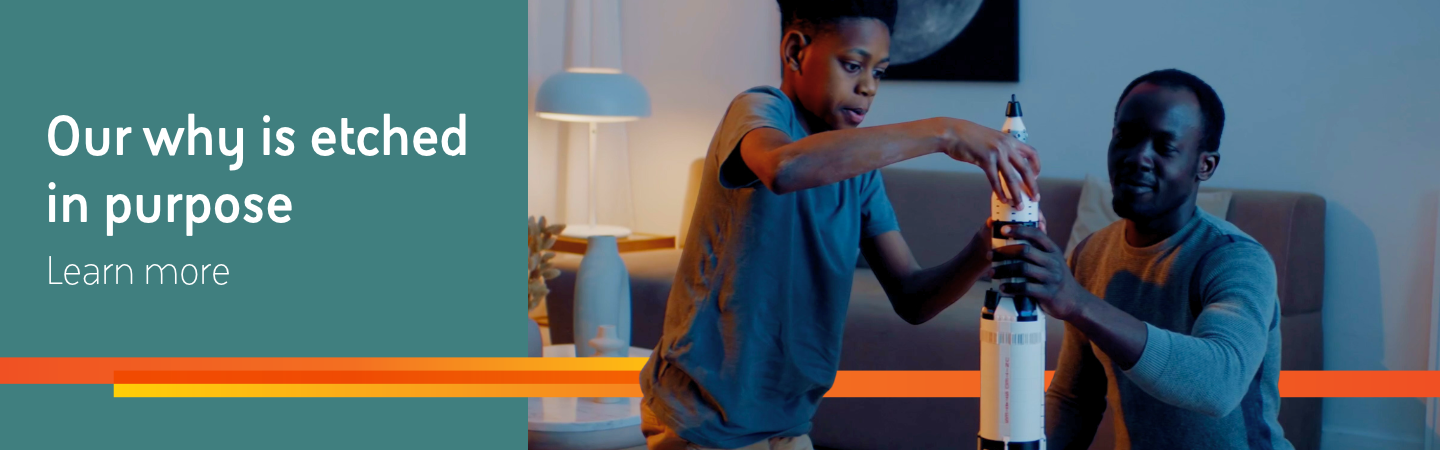 A man and a child assemble a model rocket in a living room next to the headline “Here, our why is etched in purpose” and a “Learn more” link on a teal background.