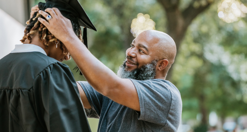Father places graduation cap on son's head