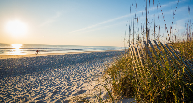 A person riding their bike on a beach in Jacksonville.