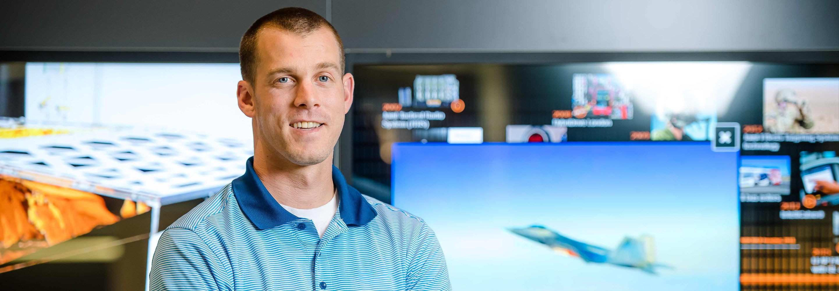 Nick, a systems engineer, poses for a photo in a BAE Systems lobby in New Hampshire.