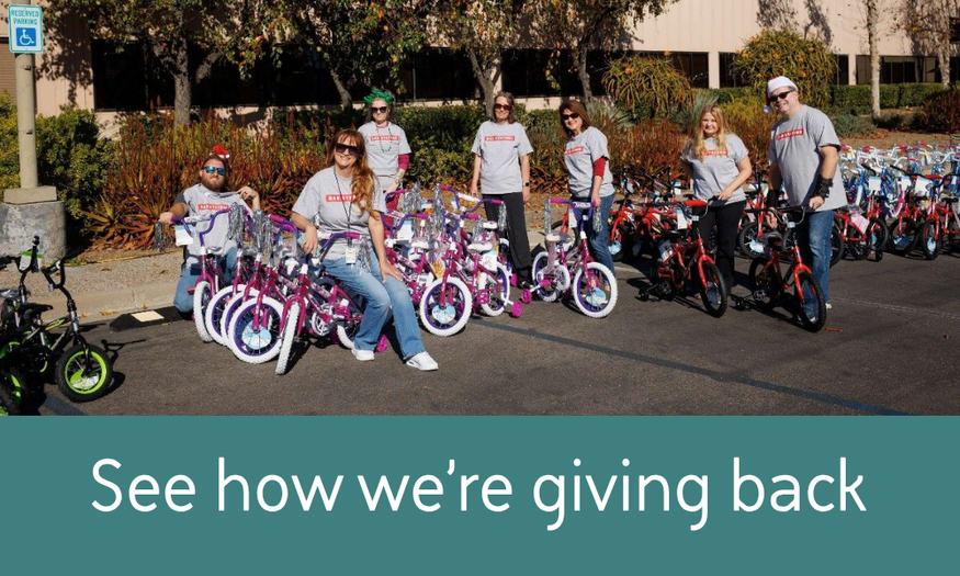 BAE Systems employees pose with children’s bicycles they are donating during a community giving event.