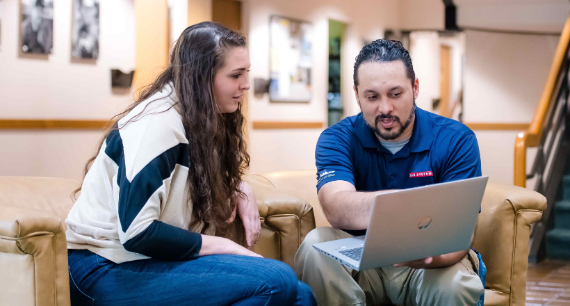 Two employees reviewing info on a laptop.