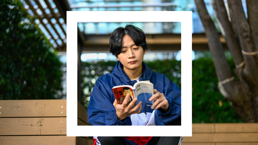 A man sitting on a bench outside reading a book framed in a white square.