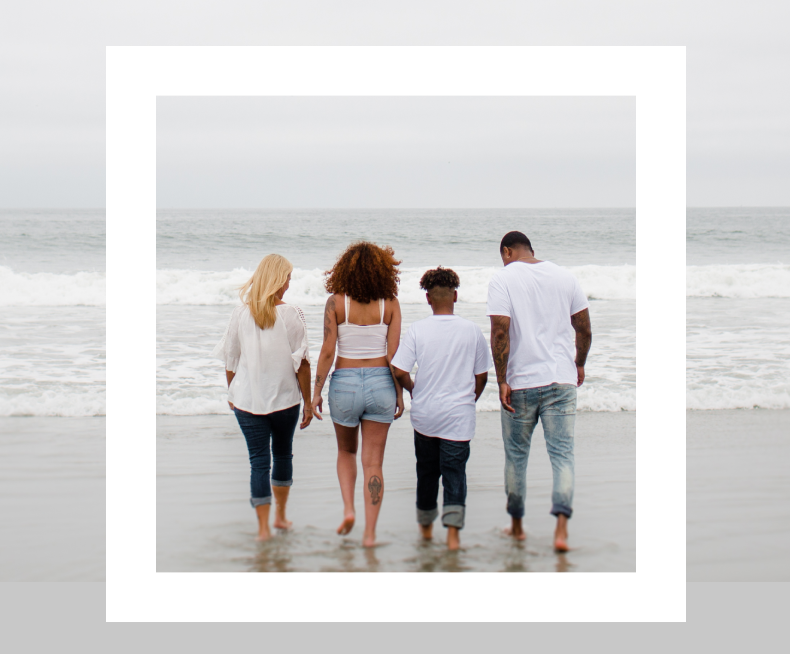 Quattro persone di spalle camminano insieme sulla riva del mare, simbolo di inclusione e senso di comunità.